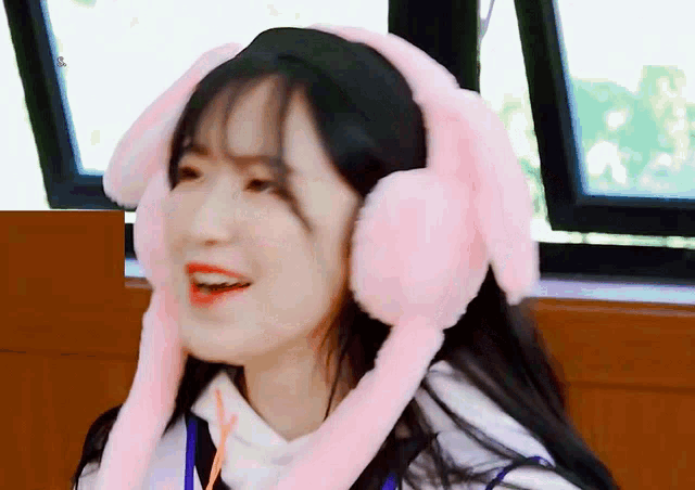 a girl wearing pink bunny ear headphones is smiling