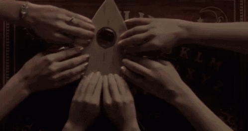 a group of people are holding a ouija board in their hands
