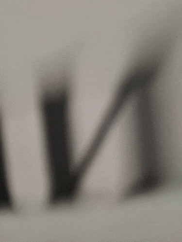 a shadow of a letter m is cast on a white surface