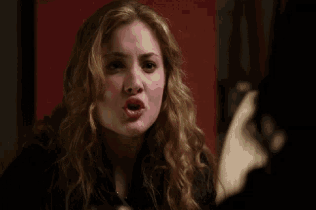 a woman with curly hair is making a funny face with her mouth open