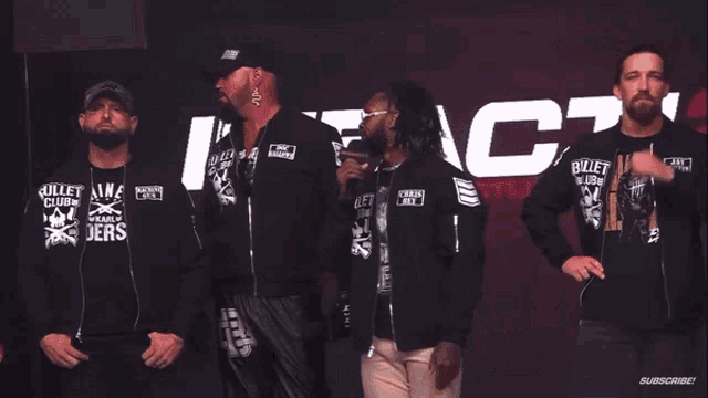 a group of men wearing bullet club shirts stand in front of a sign that says do you wanna fight about it