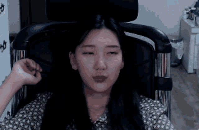 a woman is sitting in a chair with her eyes closed and her hand on her face