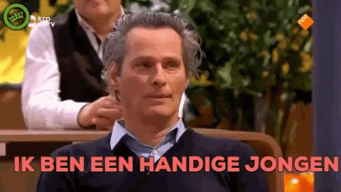 a man is sitting in front of a screen that says ik ben een handige jongen