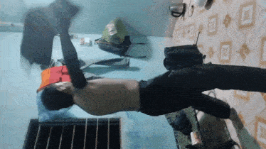 a shirtless man is doing a handstand in a bedroom