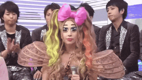 a woman with a pink bow on her head is holding a microphone in front of a group of people