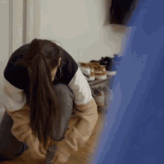 a woman wearing a ponytail is tying her shoes