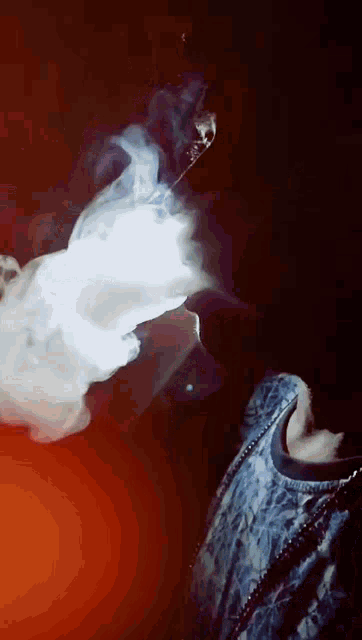 a person is smoking a hookah with smoke coming out of their mouth .