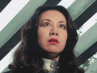a close up of a woman 's face in front of a striped wall