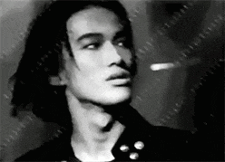 a black and white photo of a man with long hair looking at the camera