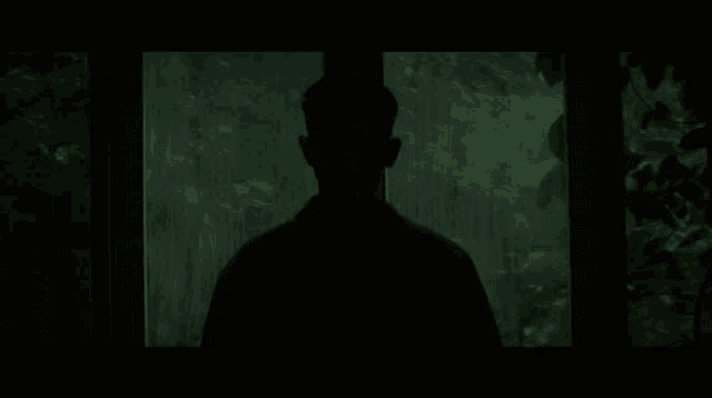 a man is standing in the rain in front of a window .