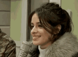a woman is smiling while holding a microphone in front of her .