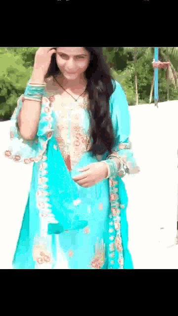 a woman in a blue dress is standing on a white surface holding a blue bag .