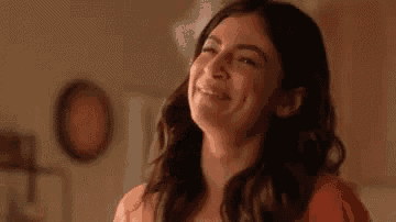 a woman is smiling with her eyes closed and her mouth open in a room .