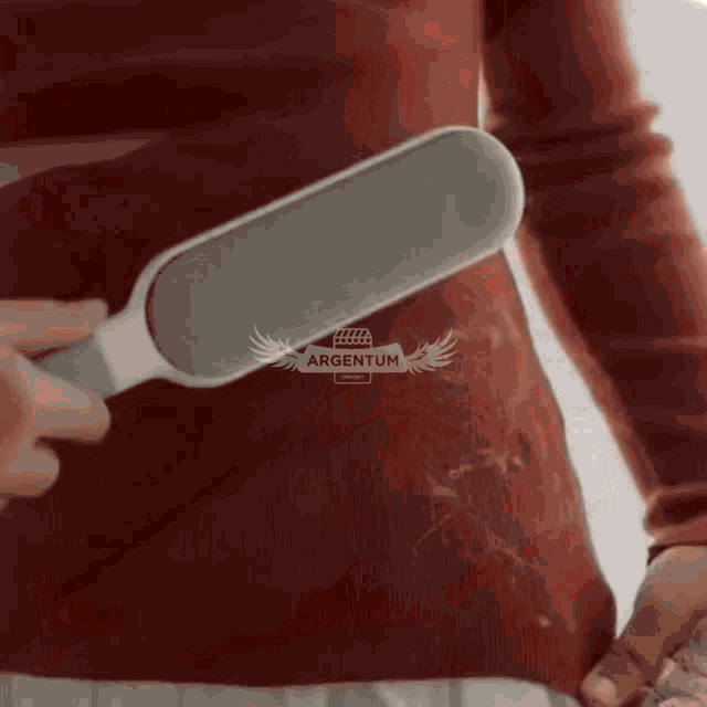 a woman is using a brush to remove hair from her sweater .