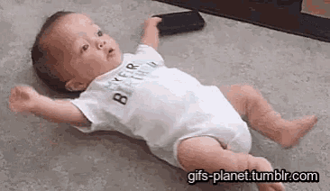 a baby is laying on his back on the floor holding a cell phone .