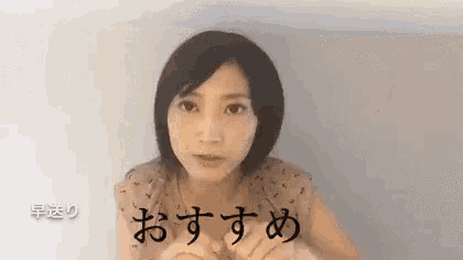 a woman with short hair is making a funny face with her hands in front of her face in a foreign language .