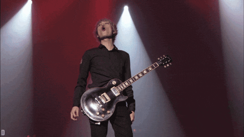 a man playing a guitar on a stage with the letter d in the corner