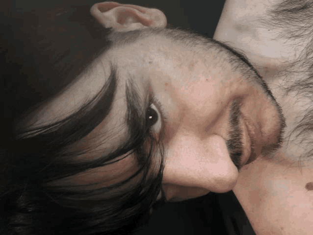 a close up of a man 's face with a beard and black hair