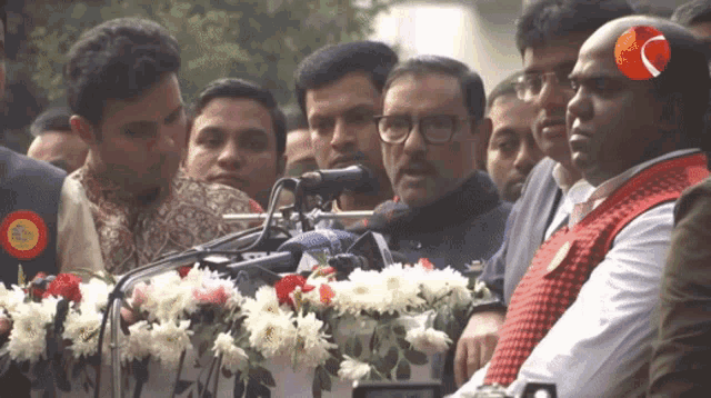 a man stands in front of a microphone wearing a badge that says ' bangladesh '