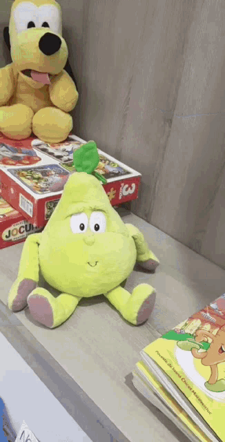 a pear shaped stuffed animal sits on a shelf next to a mickey mouse stuffed animal