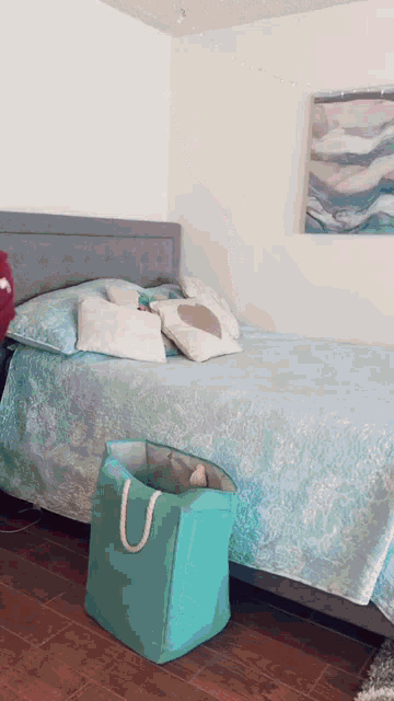 a bedroom with a bed a laundry basket and a painting on the wall