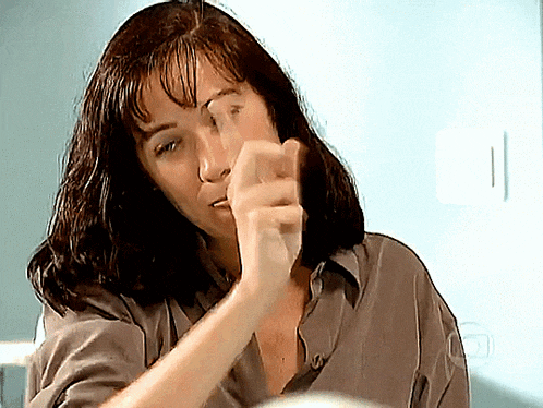 a woman in a grey shirt is pointing her finger at something