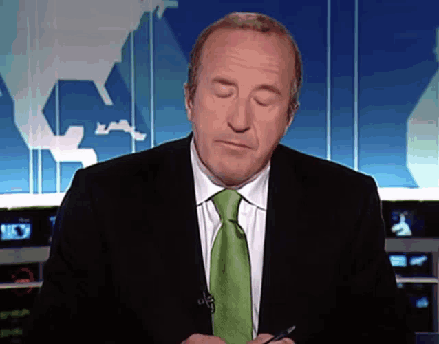 a man in a suit and green tie looks down