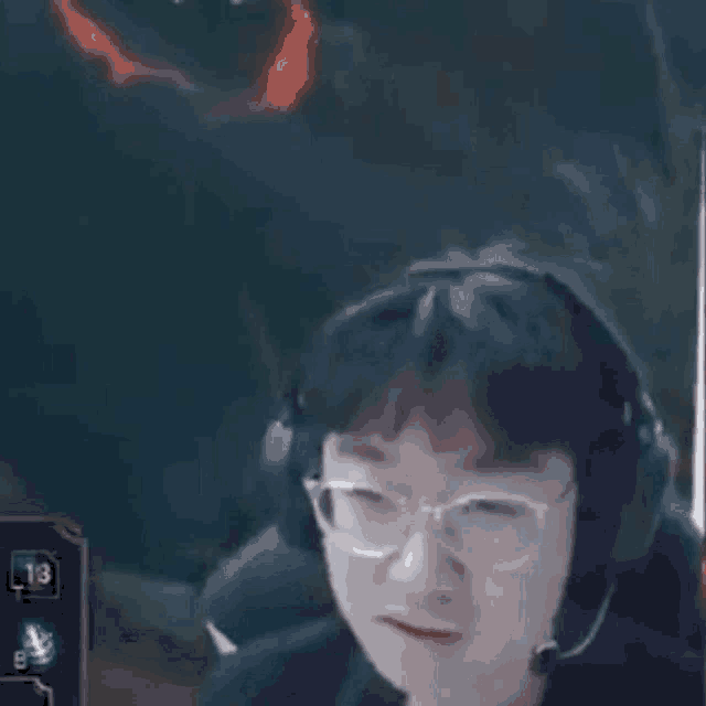 a man wearing glasses and headphones is sitting in front of a computer screen .