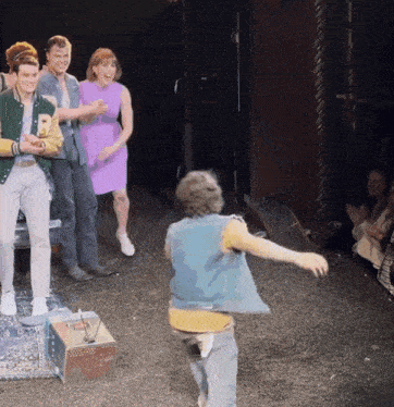 a man in a blue vest is dancing on a stage in front of a crowd