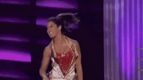 a woman is dancing on a stage in front of a purple background .