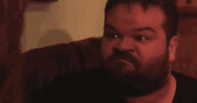 a man with a beard is sitting on a couch and says haber estudiado