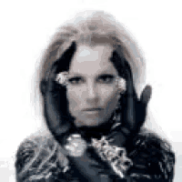 a woman wearing a black jacket and gloves is covering her face .