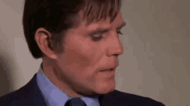 a close up of a man in a suit and tie looking down .