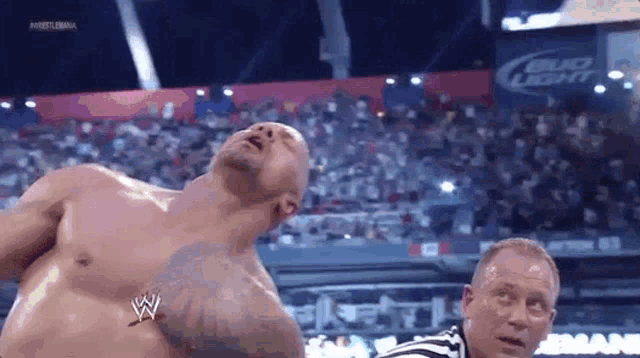 a man without a shirt is standing in front of a referee in a stadium .