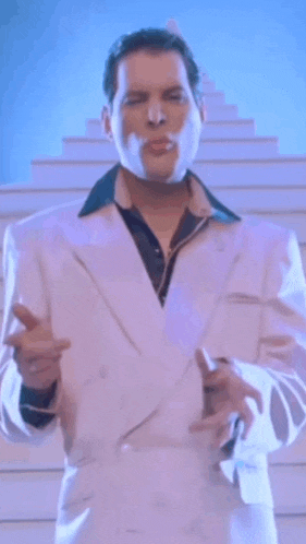 a man in a white suit is standing in front of a staircase .