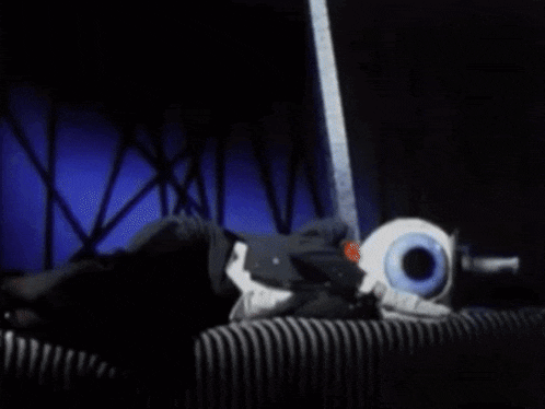 a stuffed animal with a large blue eye is laying on a striped surface