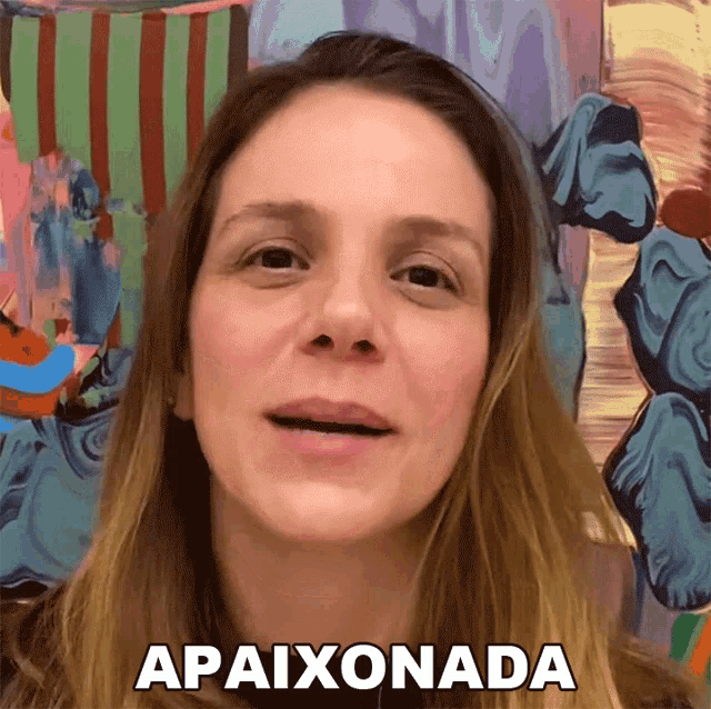 a woman in front of a colorful painting says apaixonada