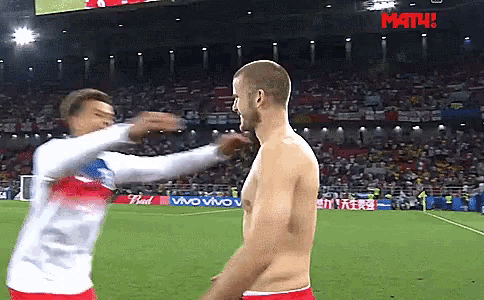 a man without a shirt is being tackled by another man on a soccer field with a math sign in the background