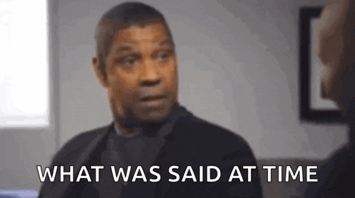a man in a suit is sitting on a couch talking to another man and says `` what was said at time '' .