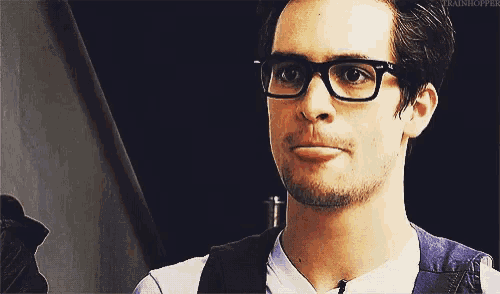 a close up of a man wearing glasses and a vest .