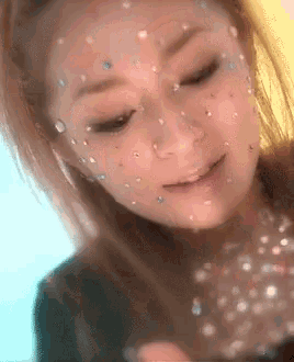 a woman with rhinestones on her face looks down at something
