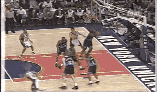 a basketball game is being played in front of a new york knicks sign