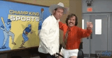 a man in a cowboy hat is standing next to another man in front of a sign that says champ kind sports