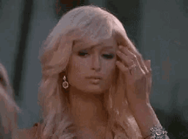 a close up of a woman with blonde hair and earrings .
