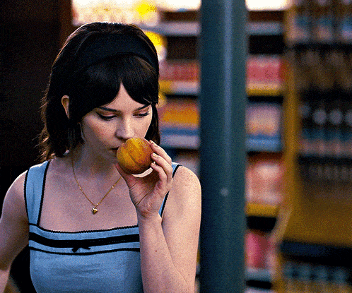 a woman is eating a peach in a store