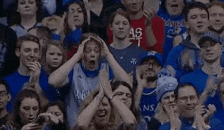 a group of people are sitting in a stadium watching a game and one of them is holding his head .