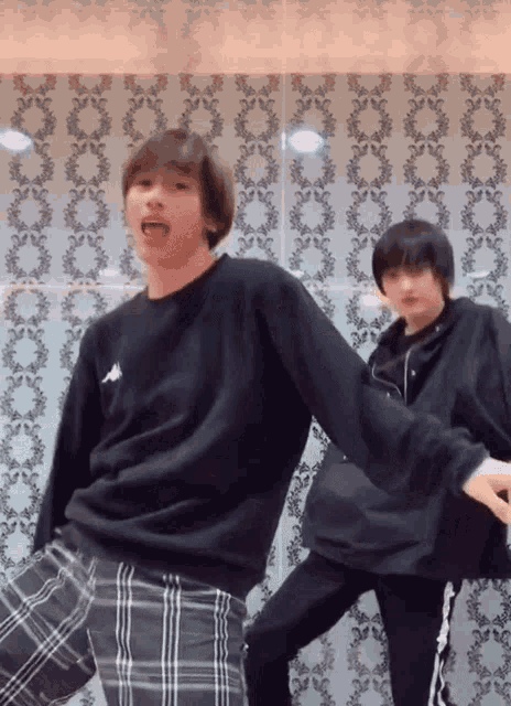 a man wearing a black kappa sweatshirt is dancing with another man