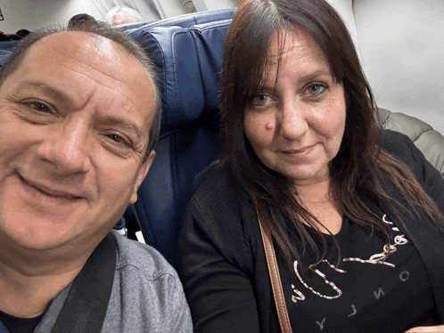 a man and woman are posing for a picture on an airplane and the woman is wearing a shirt that says yjmo