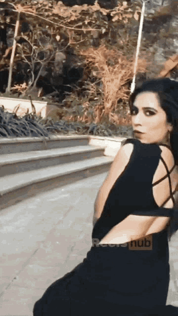 a woman in a black dress is kneeling down in front of a sign that says " pornhub "