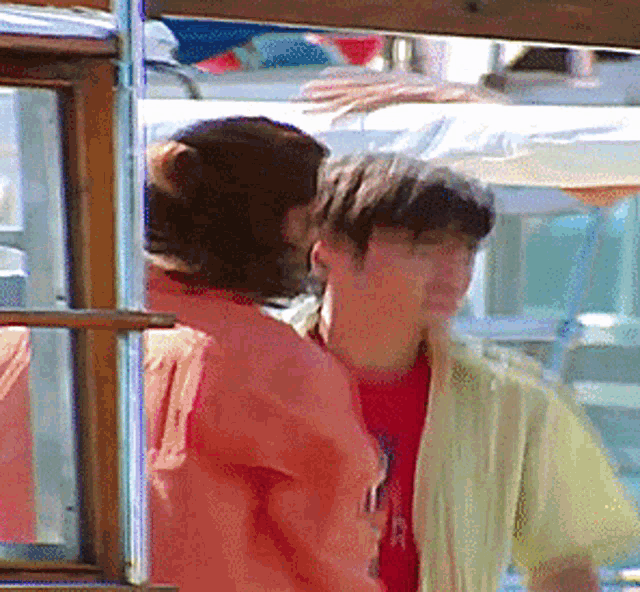 a man in a yellow shirt talks to another man in an orange shirt